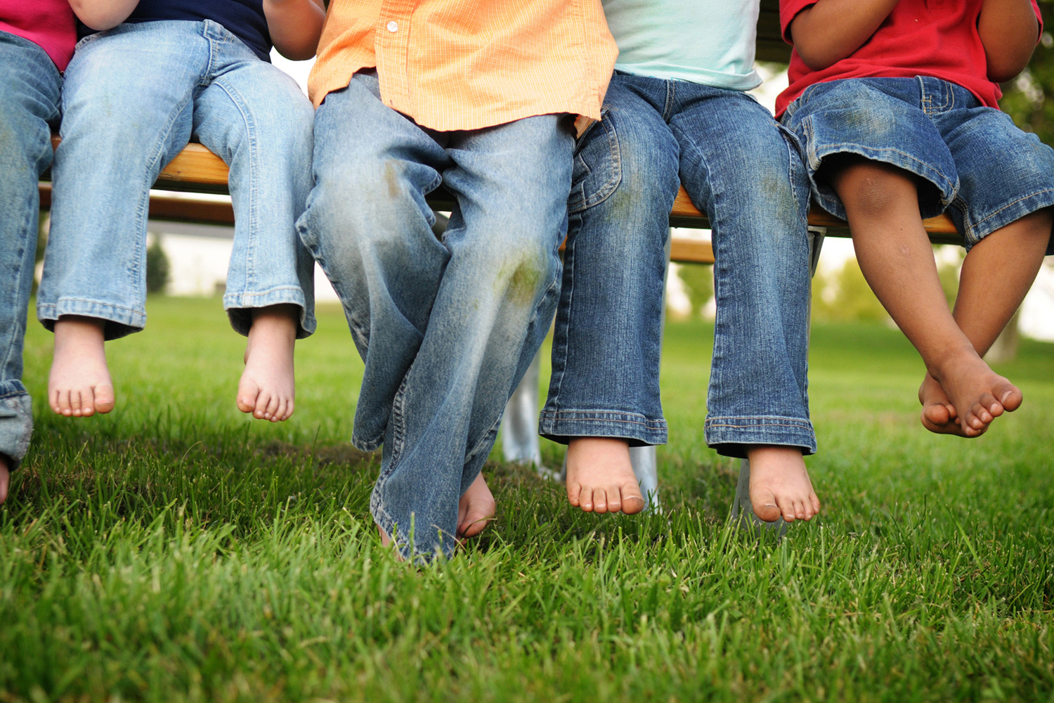 barefoot kids sitting on a bench